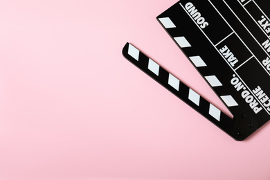 Photo of Clapper board on pink background, top view with space for text. Cinema production