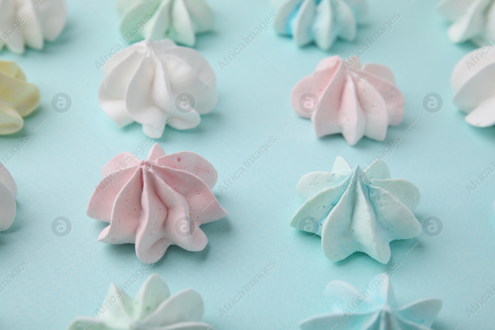 Photo of Delicious meringue cookies on light blue background, closeup