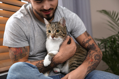 Photo of Man with tabby cat near window indoors, closeup. Friendly pet