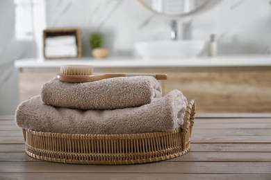 Photo of Clean towels and shower brush on wooden table in bathroom