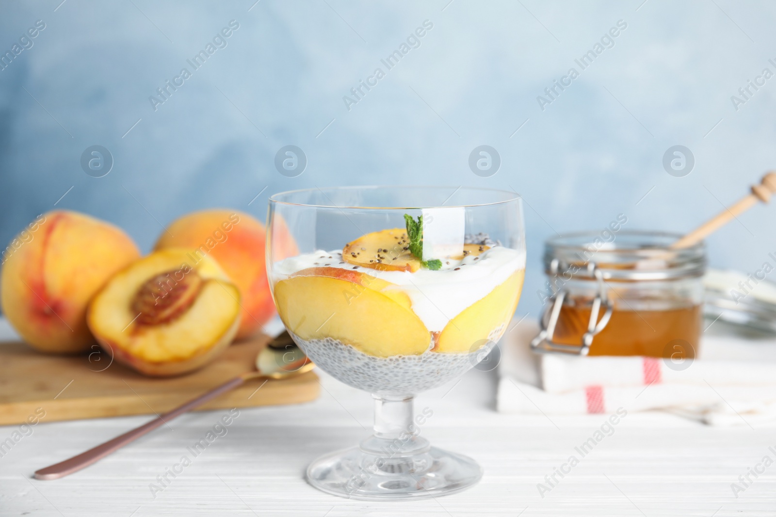 Photo of Tasty peach dessert with yogurt and chia seeds served on white wooden table