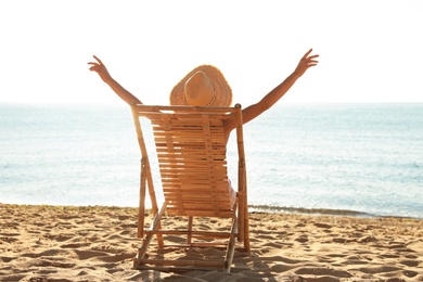 Woman relaxing on deck chair at sandy beach. Summer vacation