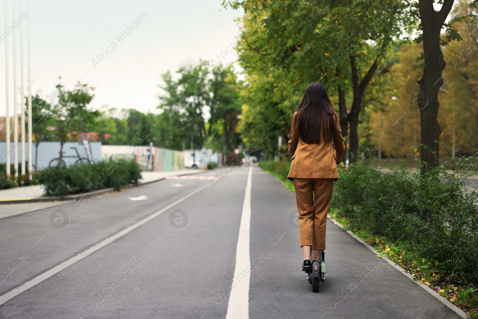 Photo of Businesswoman riding electric kick scooter outdoors, back view. Space for text