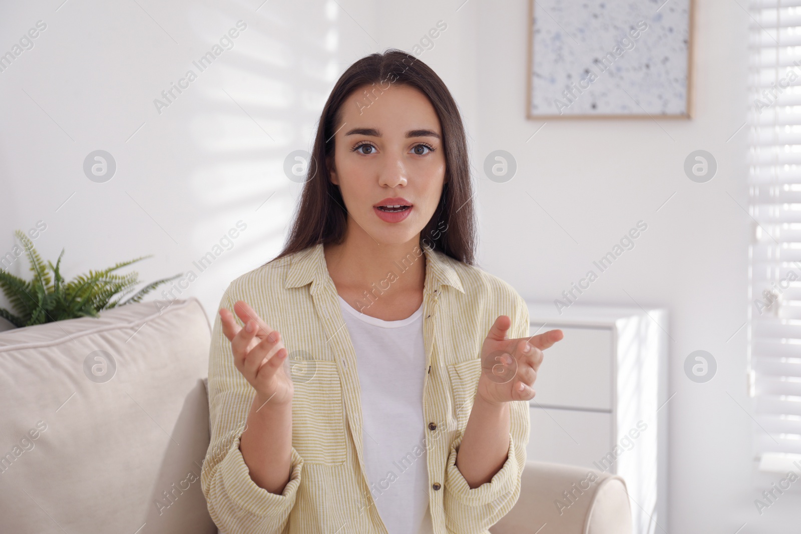 Photo of Young woman talking with her coworkers on video call indoors, view from web camera