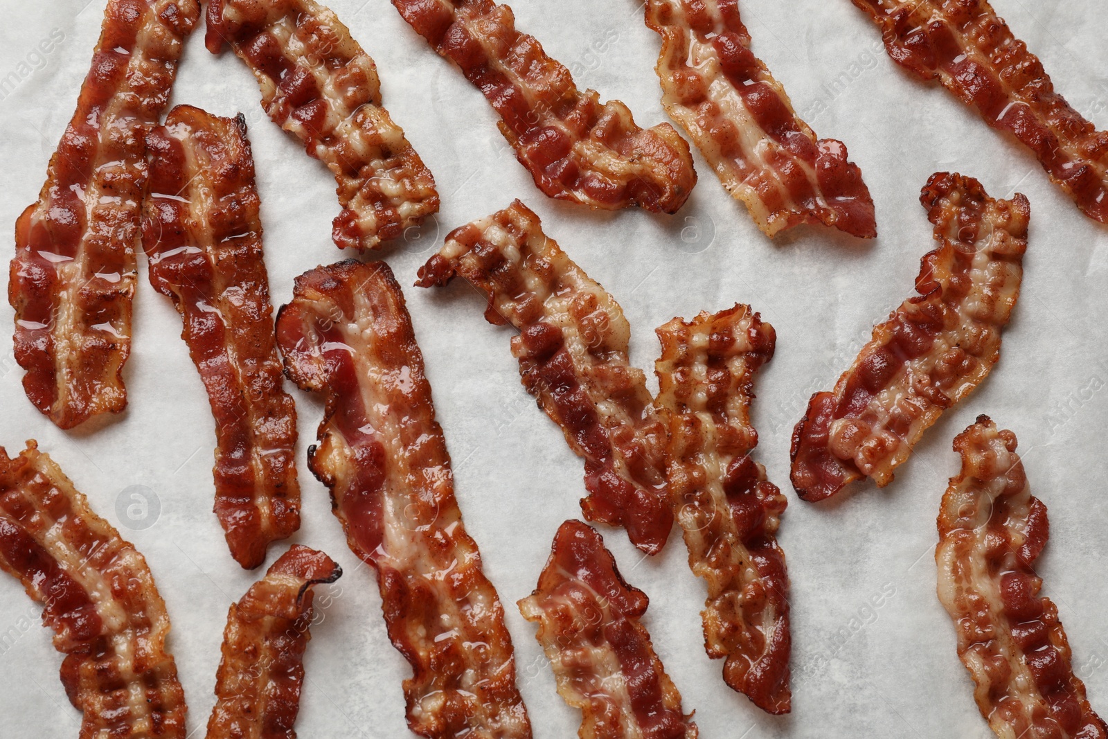 Photo of Slices of tasty fried bacon on white table, top view