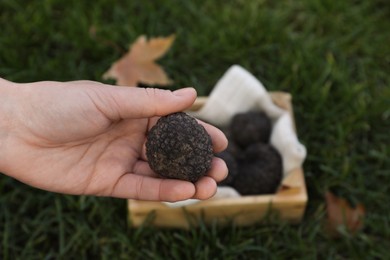 Photo of Woman holding fresh truffle in hand outdoors, closeup