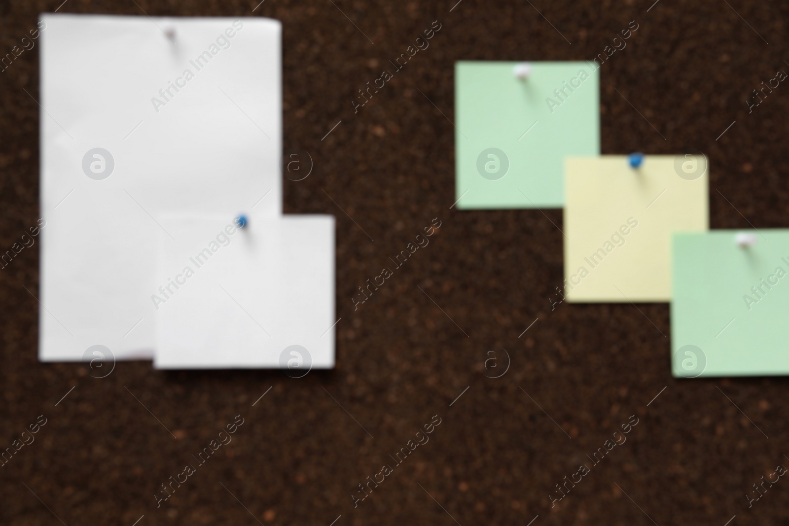 Photo of Blurred view of dark corkboard with pinned notes