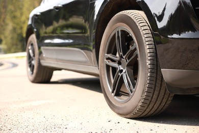 Photo of Modern black car parked on asphalt road outdoors