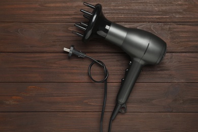 Photo of Hair dryer on wooden table, top view. Professional hairdresser tool