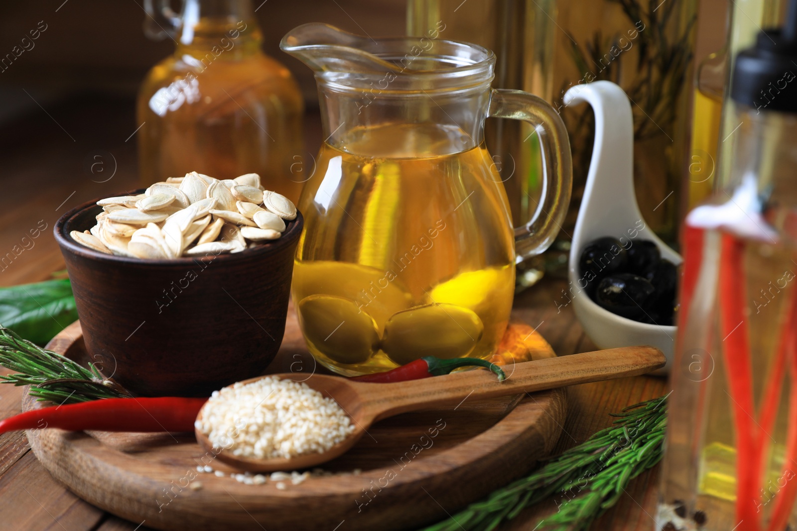 Photo of Jug of cooking oil and ingredients on wooden table