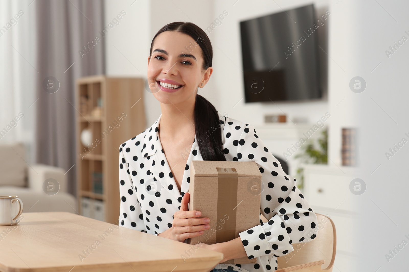 Photo of Happy young woman with parcel at home. Internet shopping