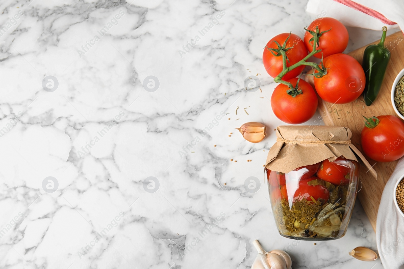 Photo of Flat lay composition with pickled tomatoes in glass jar on white marble table, space for text