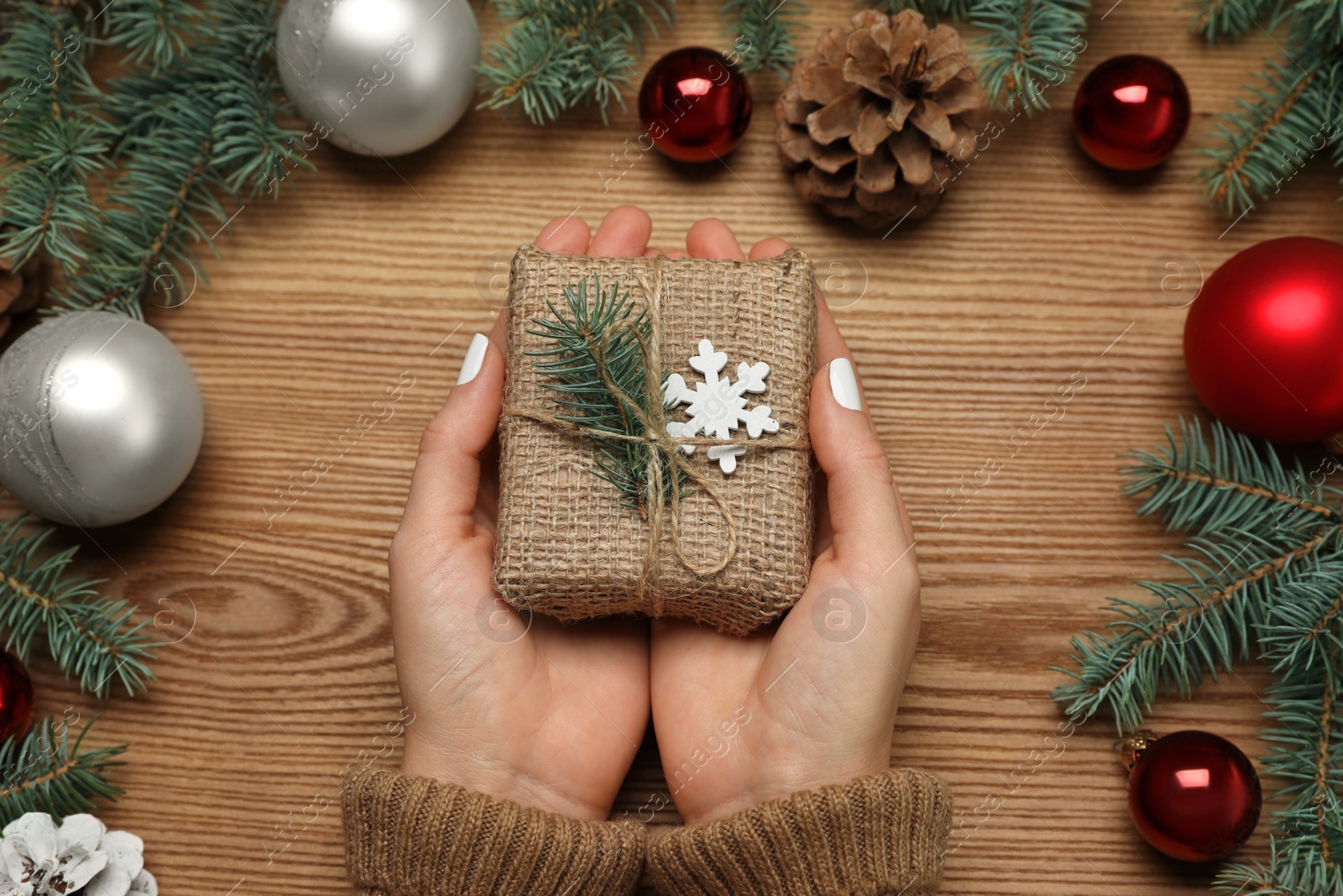 Photo of Woman with Christmas gift at wooden table, top view