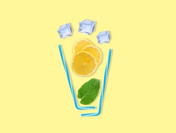 Image of Creative lemonade layout with lemon slices, mint, ice cubes and straws on yellow background, top view