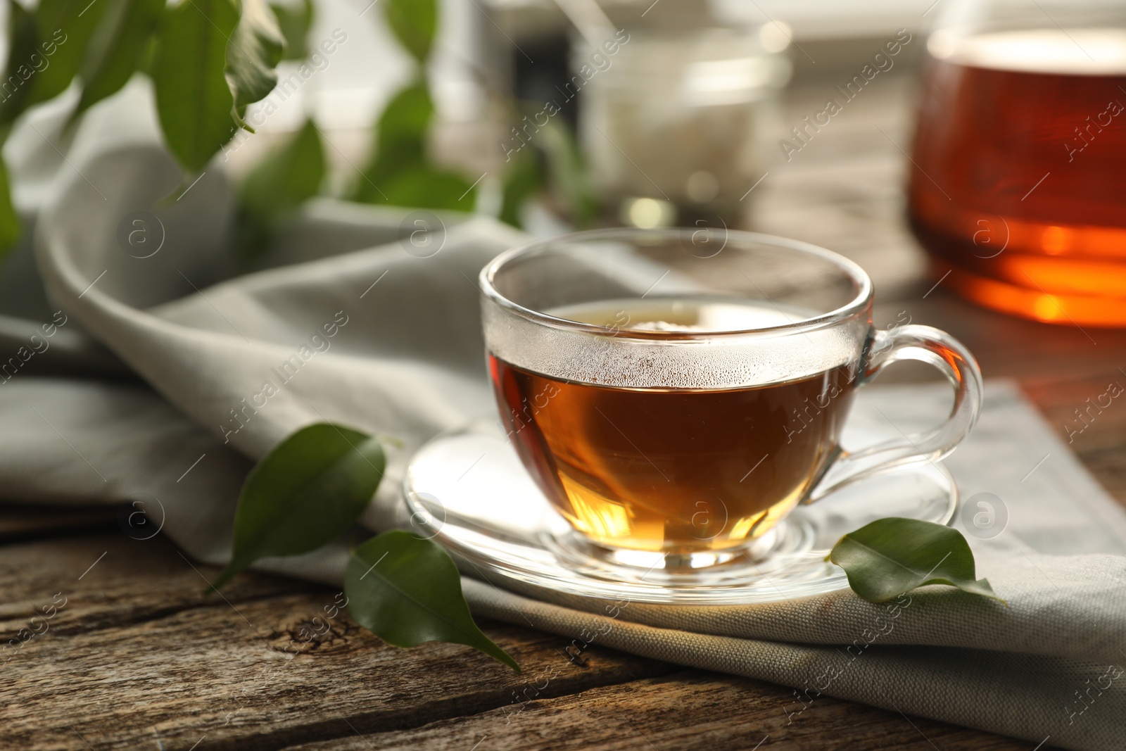 Photo of Tasty tea in cup on wooden table, closeup