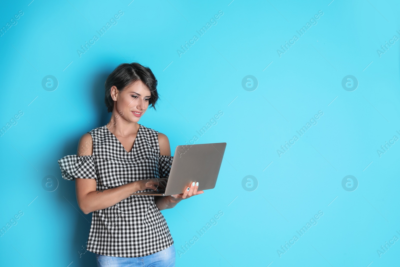 Photo of Young woman with modern laptop on color background