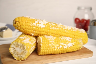 Fresh corn cobs with butter on wooden table, closeup