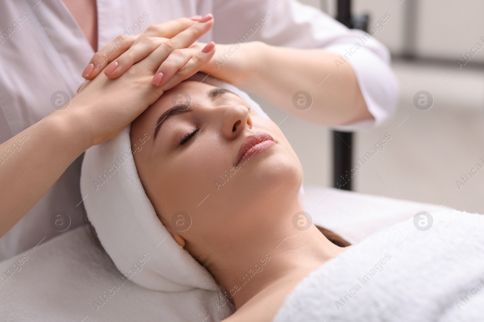 Photo of Cosmetologist making face massage to client in clinic, closeup