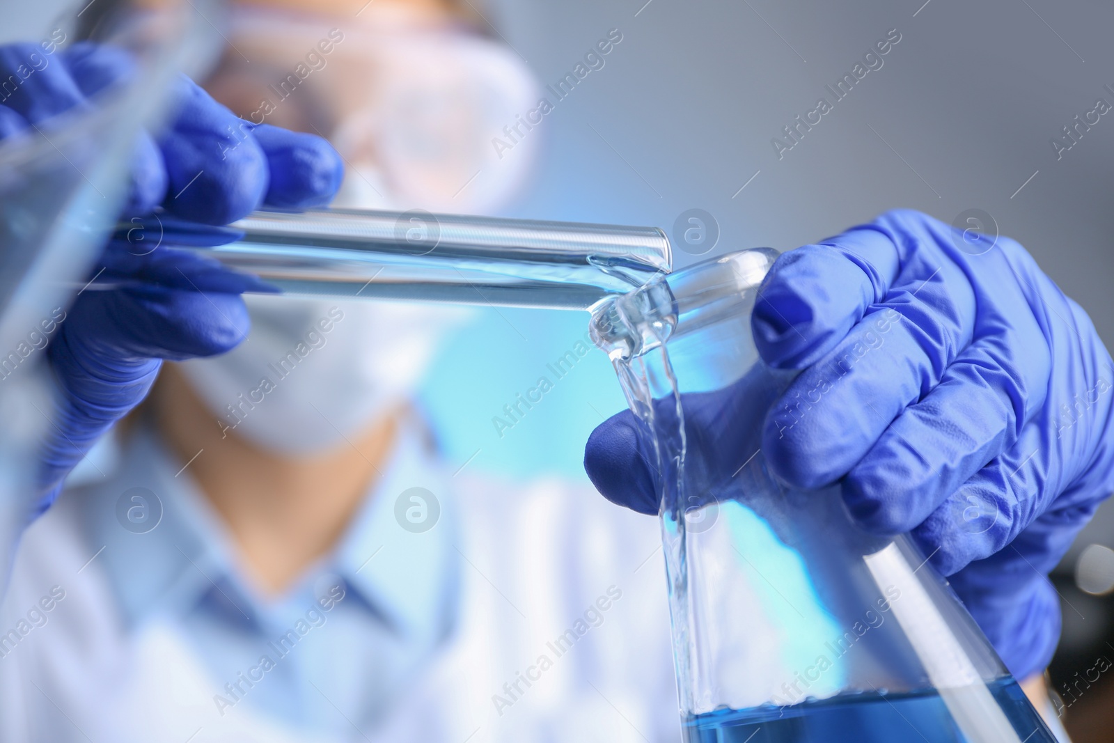 Photo of Doctor pouring blue liquid into flask, closeup. Laboratory analysis
