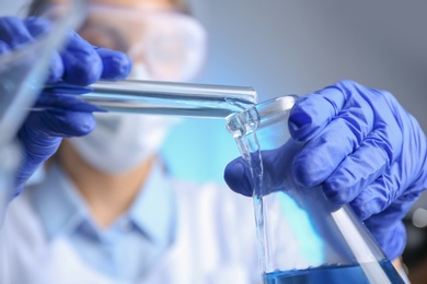 Doctor pouring blue liquid into flask, closeup. Laboratory analysis