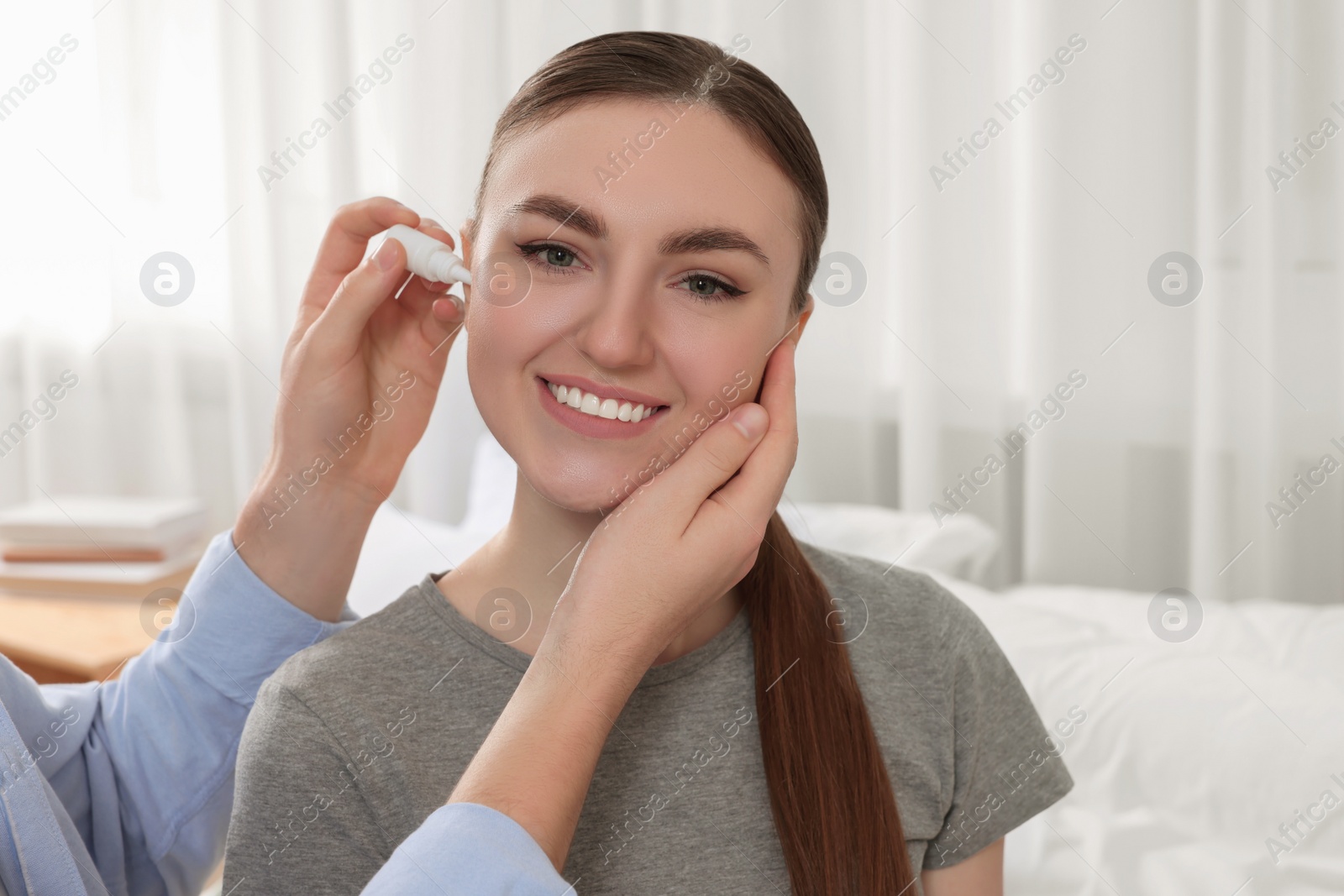 Photo of Man dripping medication into woman's ear at home
