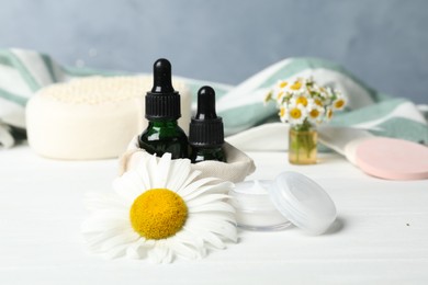 Cosmetic products and chamomile on white table