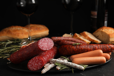 Different tasty sausages on black table, closeup