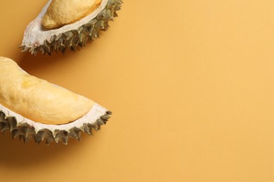 Photo of Pieces of fresh ripe durian on orange background, flat lay. Space for text