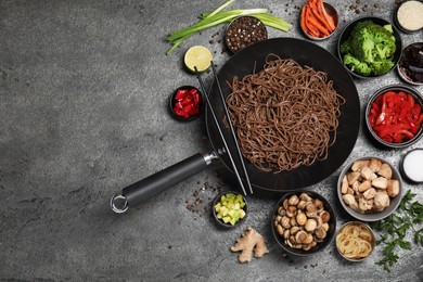 Photo of Wok with noodles, chicken and other products on grey table, flat lay. Space for text