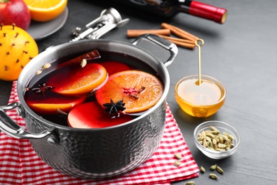 Delicious mulled wine and ingredients on grey table