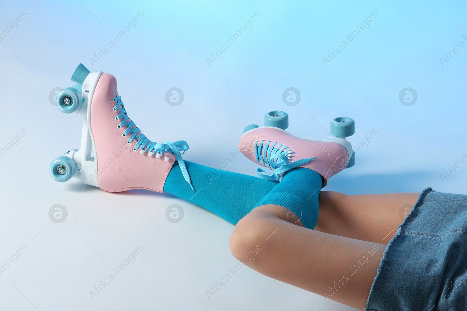 Photo of Woman with vintage roller skates on color background, closeup