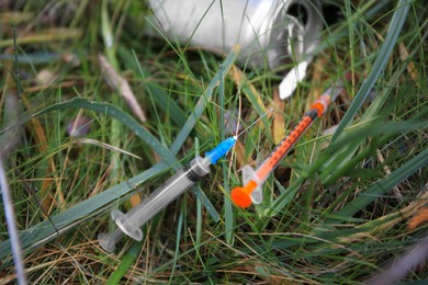 Photo of Disposable syringes with needles on green grass outdoors