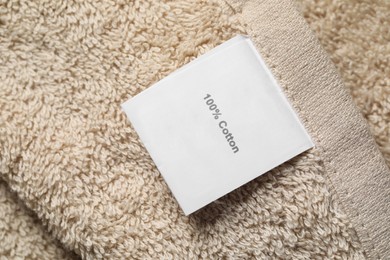 Photo of Clothing label on beige fluffy towel, top view