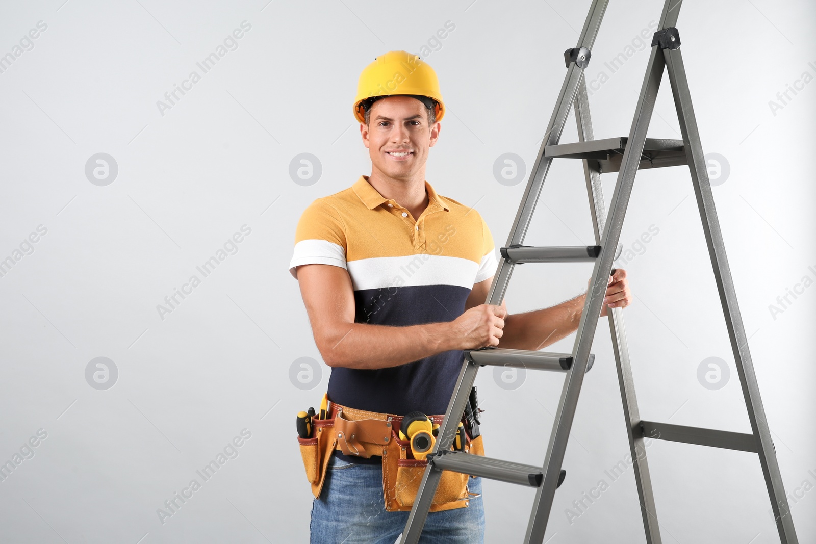 Photo of Professional builder with metal ladder on grey background