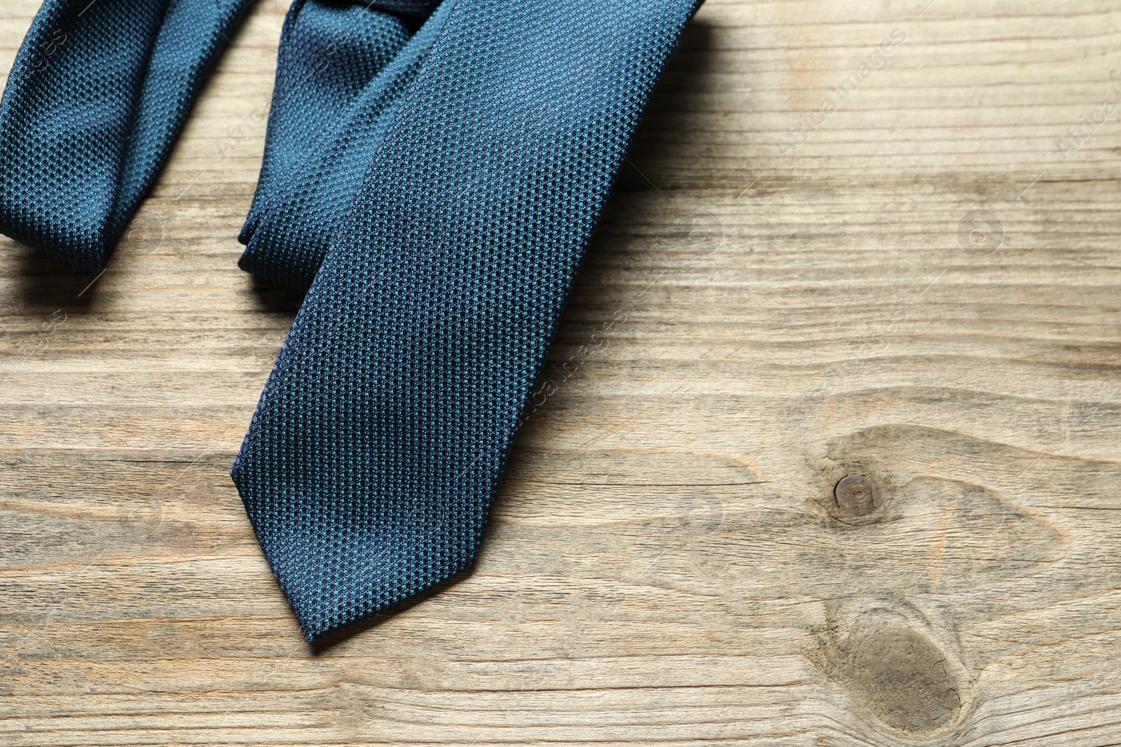 Photo of One blue necktie on light wooden table, top view. Space for text