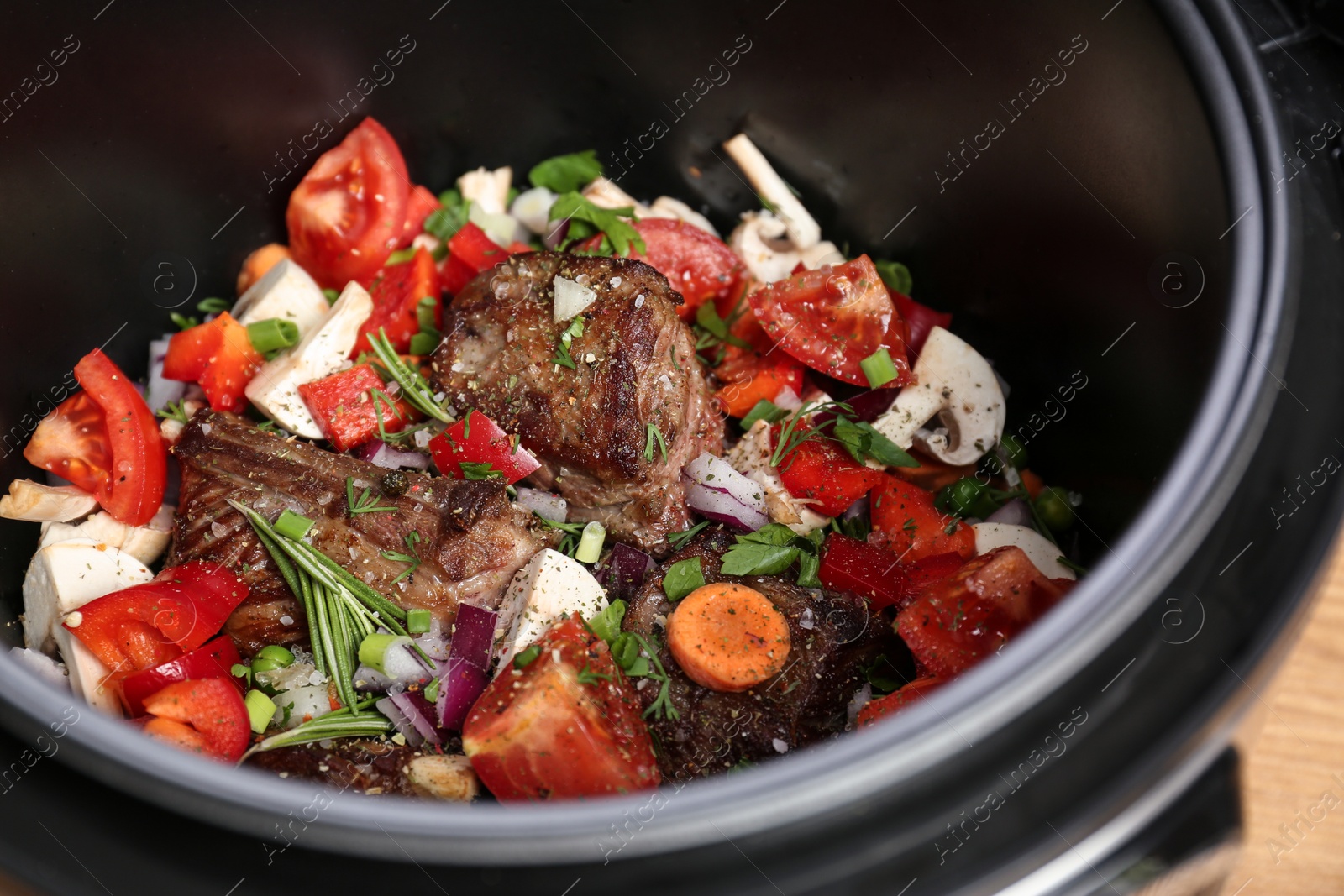 Photo of Delicious pork ribs with vegetables in multi cooker, closeup