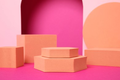 Photo of Many orange geometric figures on pink background. Stylish presentation for product