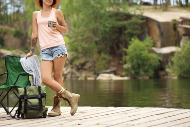 Young woman resting on pier near lake. Camping season