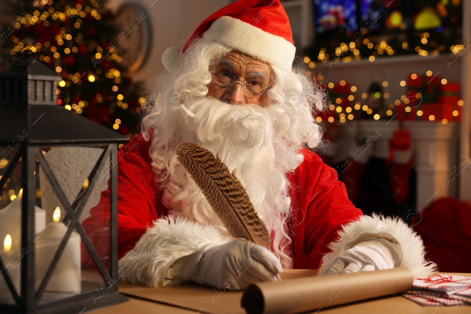 Photo of Santa Claus writing letter at table in room decorated for Christmas