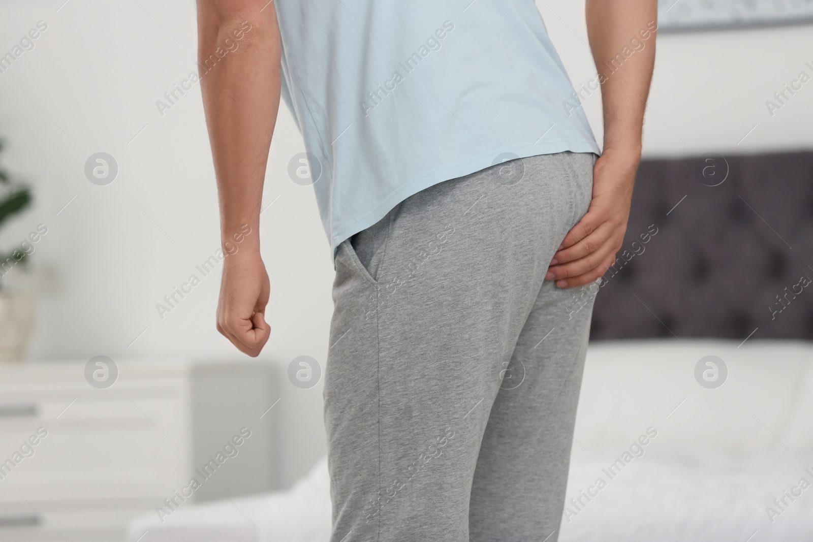 Photo of Man suffering from hemorrhoid in bedroom, closeup