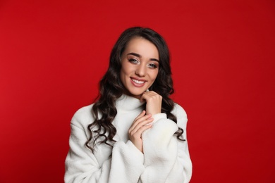 Beautiful young woman wearing warm sweater on red background. Christmas party