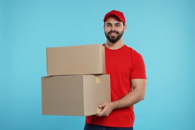 Happy courier with parcels on light blue background