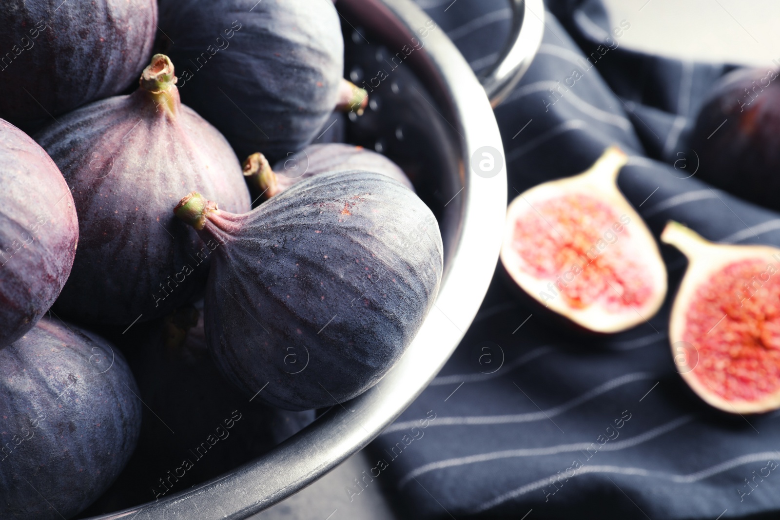 Photo of Colander with fresh ripe figs on table, closeup. Tropical fruit