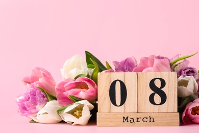 Wooden block calendar with date 8th of March and tulips on pink background, space for text. International Women's Day