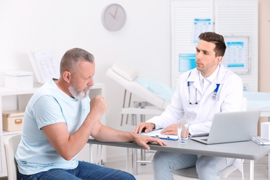 Photo of Coughing mature man visiting doctor at clinic