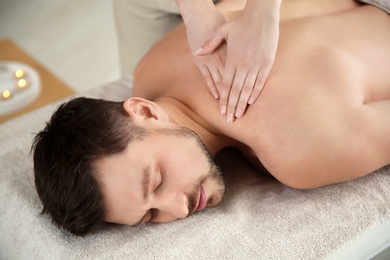 Handsome man receiving back massage in spa salon