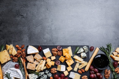 Cheese plate with grapes and nuts on dark table, top view. Space for text