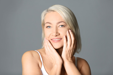 Portrait of beautiful mature woman on grey background