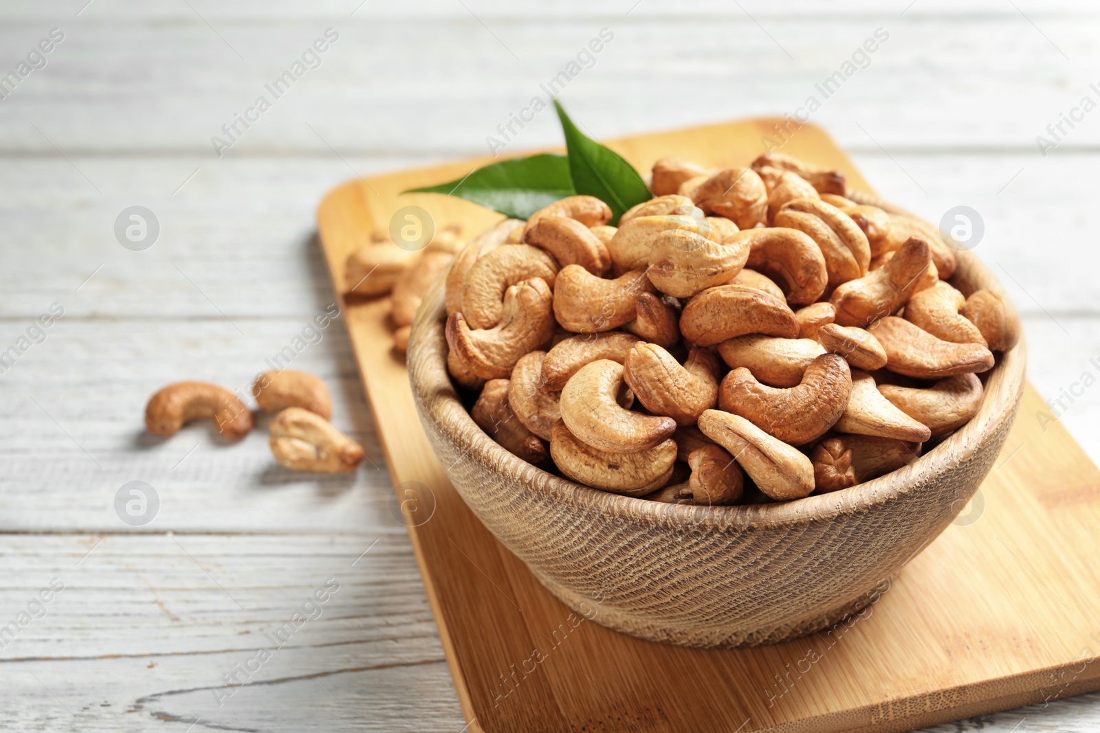 Photo of Bowl with cashew nuts on wooden table. Space for text