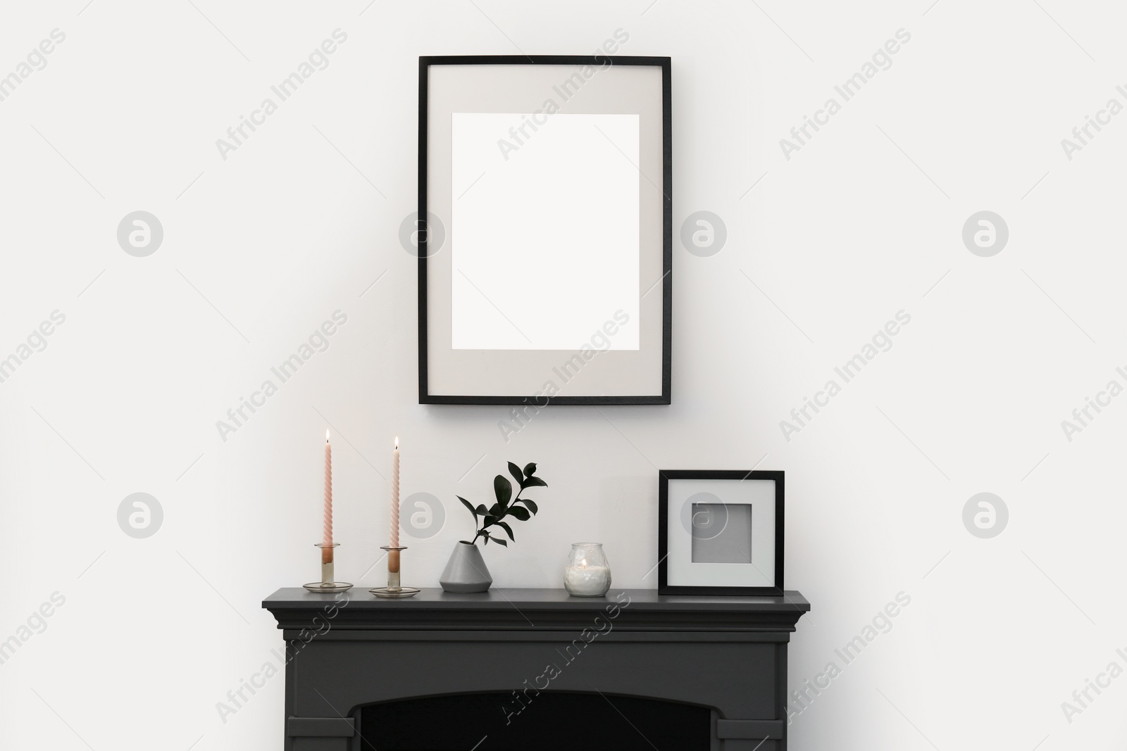 Photo of Fireplace, decorative elements and photo frames in room with light wall. Interior design